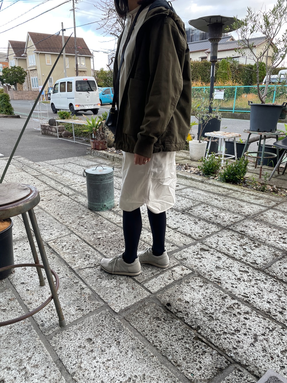 グレー系のスニーカー、ホワイト系のワンピース、グリーン系のミリタリージャケットを着用したレディースの冬コーディネートの2枚目の写真