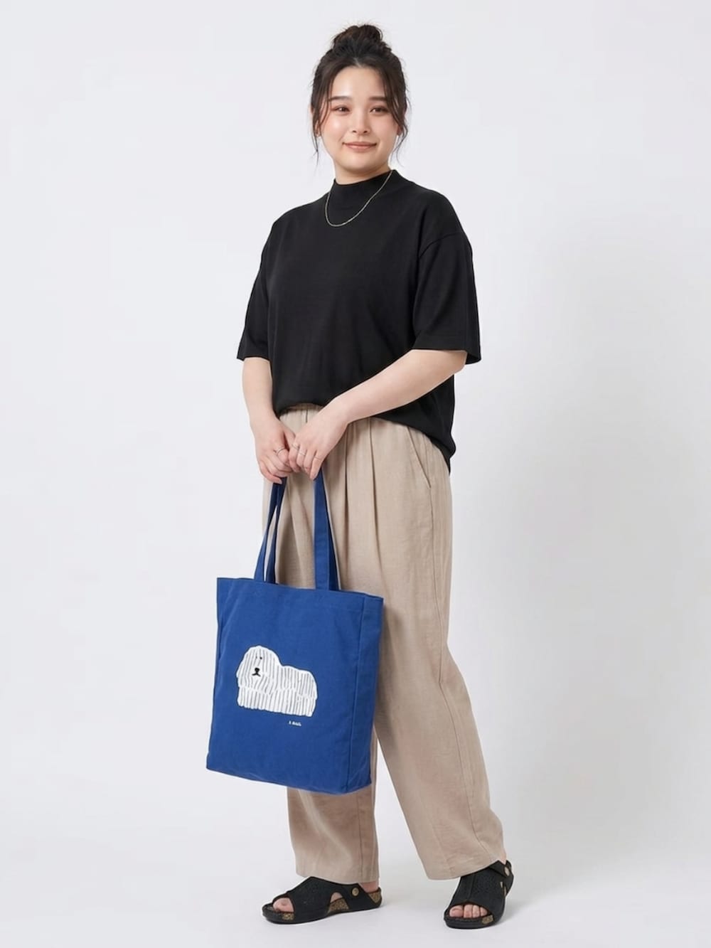ベージュ系のパンツ、ブルー系のトートバッグ、ブラック系のニット/セーターを着用したレディースの夏コーディネートの3枚目の写真