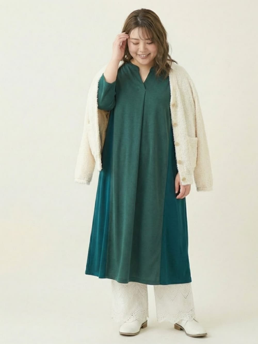 ホワイト系のカーディガン/ボレロ、グリーン系のワンピース、ホワイト系のパンツを着用したレディースの冬コーディネートの2枚目の写真