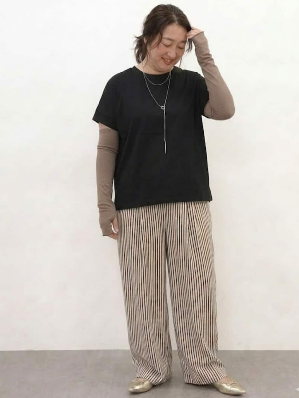 ブラック系のTシャツ/カットソー、ブラウン系のパンツ、ブラウン系の手袋を着用したレディースの春コーディネートの2枚目の写真