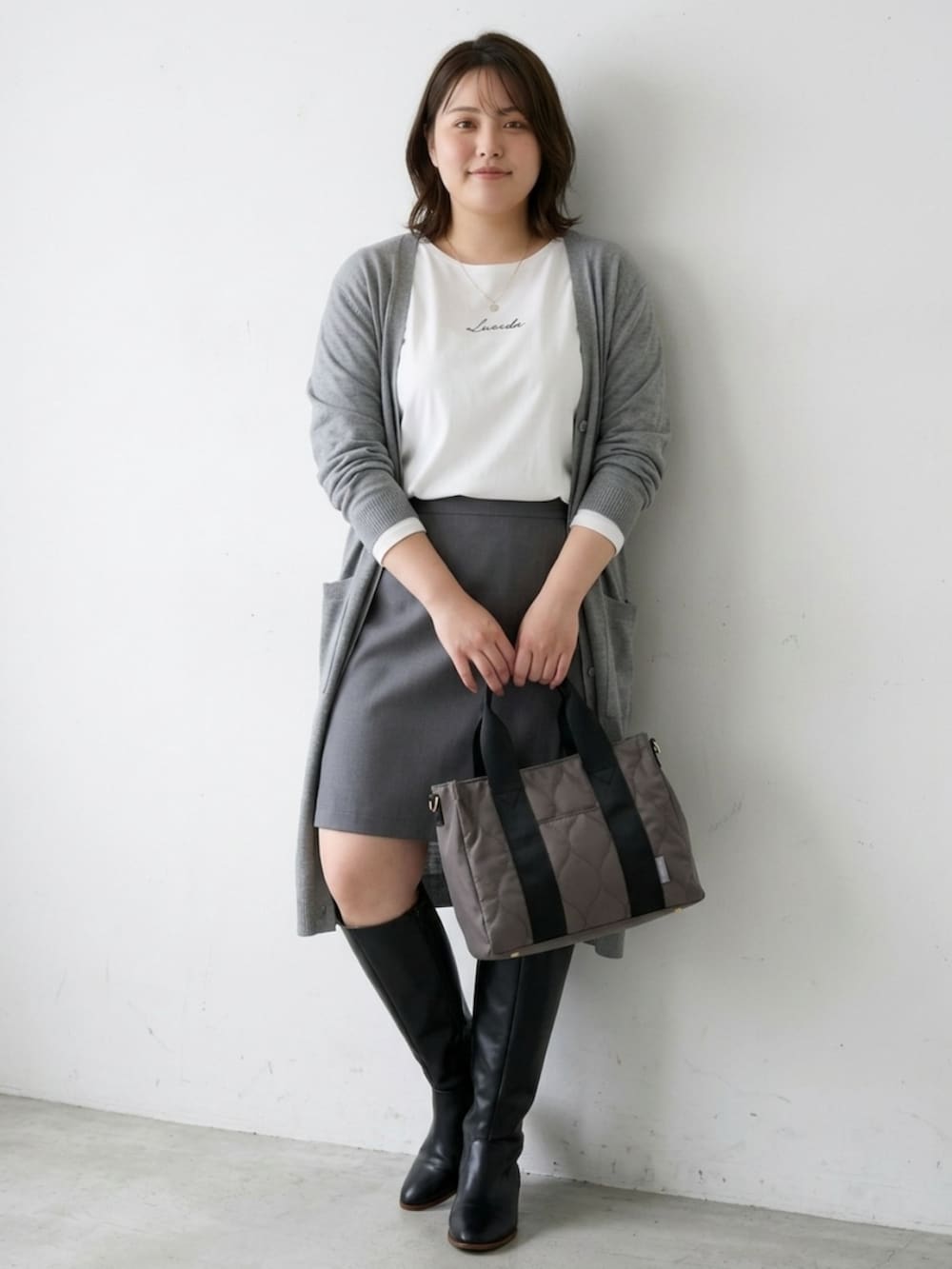 グレー系のトートバッグ、ホワイト系のTシャツ/カットソー、グレー系のカーディガン/ボレロを着用したレディースの秋コーディネートの3枚目の写真