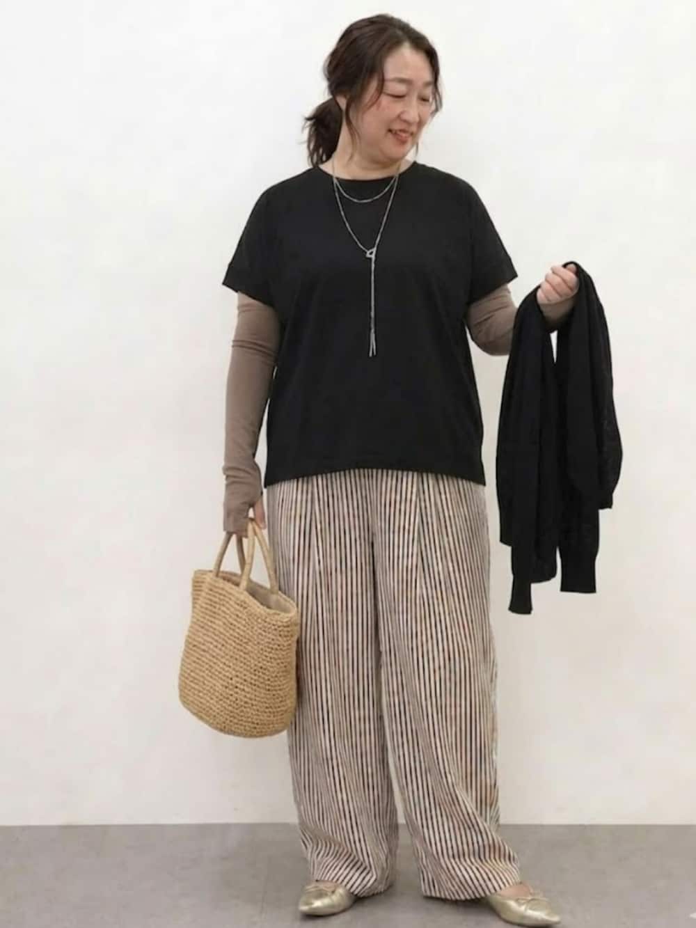 ブラック系のTシャツ/カットソー、ブラウン系のパンツ、ブラウン系の手袋を着用したレディースの春コーディネートの3枚目の写真