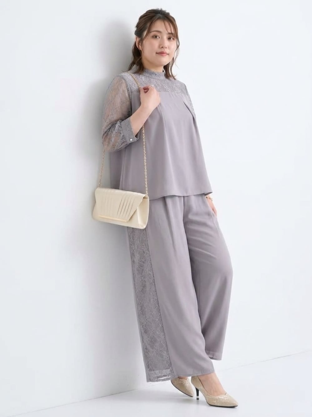 ゴールド系のバッグ、ベージュ系のパンプス、グレー系のパンツドレスを着用したレディースの秋コーディネートの3枚目の写真