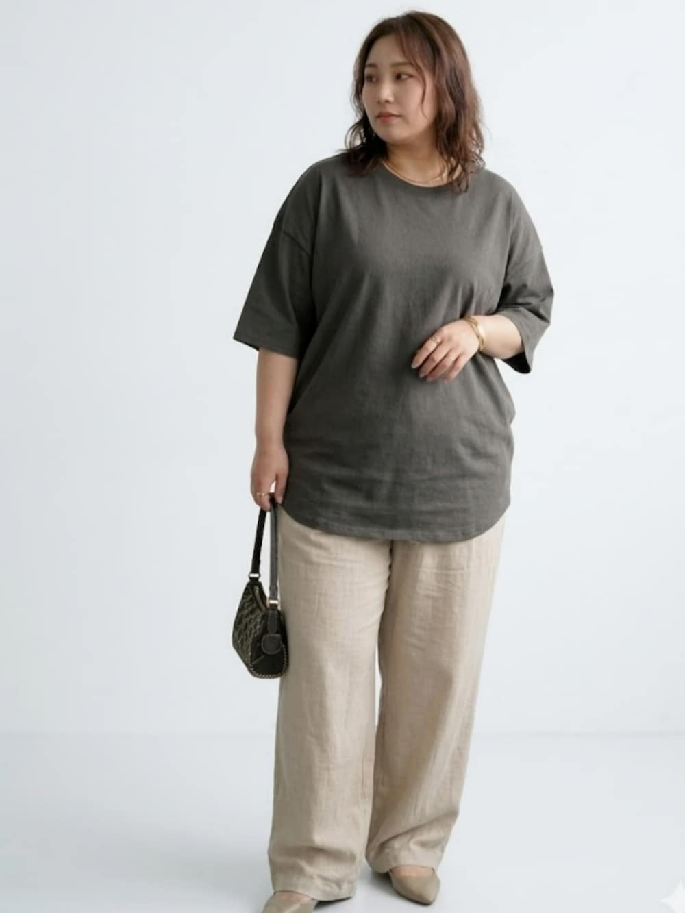 シルバー系のトートバッグ、ベージュ系のパンツ、グレー系のチュニックを着用したレディースの春コーディネートの2枚目の写真