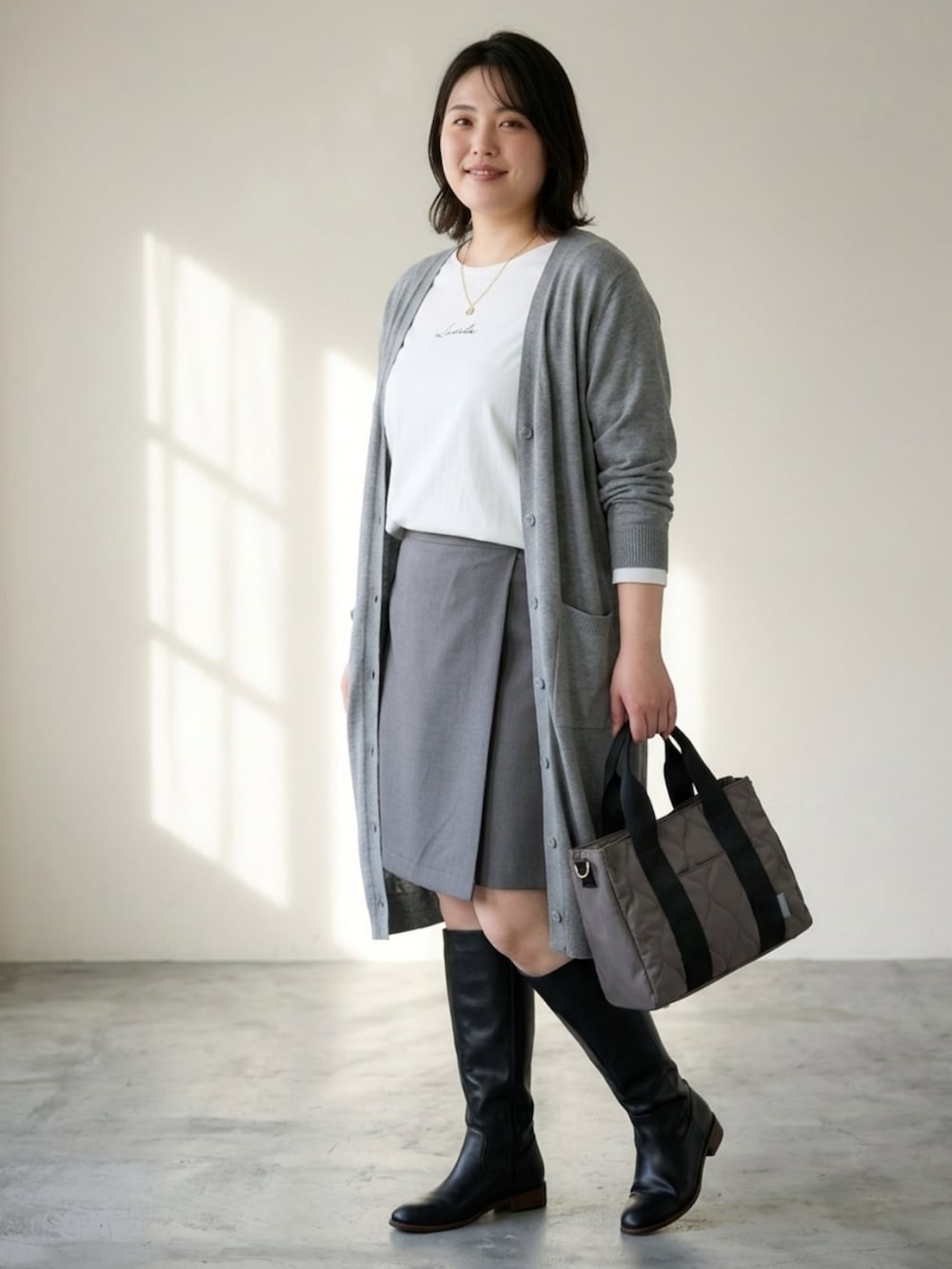 グレー系のトートバッグ、ホワイト系のTシャツ/カットソー、グレー系のカーディガン/ボレロを着用したレディースの秋コーディネートの4枚目の写真