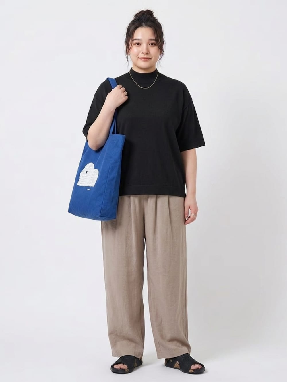 ベージュ系のパンツ、ブルー系のトートバッグ、ブラック系のニット/セーターを着用したレディースの夏コーディネートの2枚目の写真