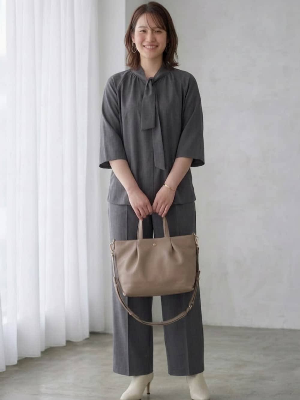 ベージュ系のショルダーバッグ、グレー系のシャツ/ブラウス、グレー系のその他パンツを着用したレディースの春コーディネートの2枚目の写真