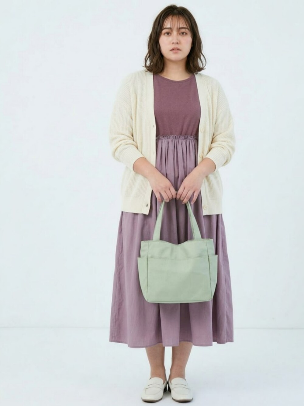 ピンク系のワンピース、ホワイト系のカーディガン/ボレロ、グリーン系のトートバッグを着用したレディースの春コーディネートの2枚目の写真