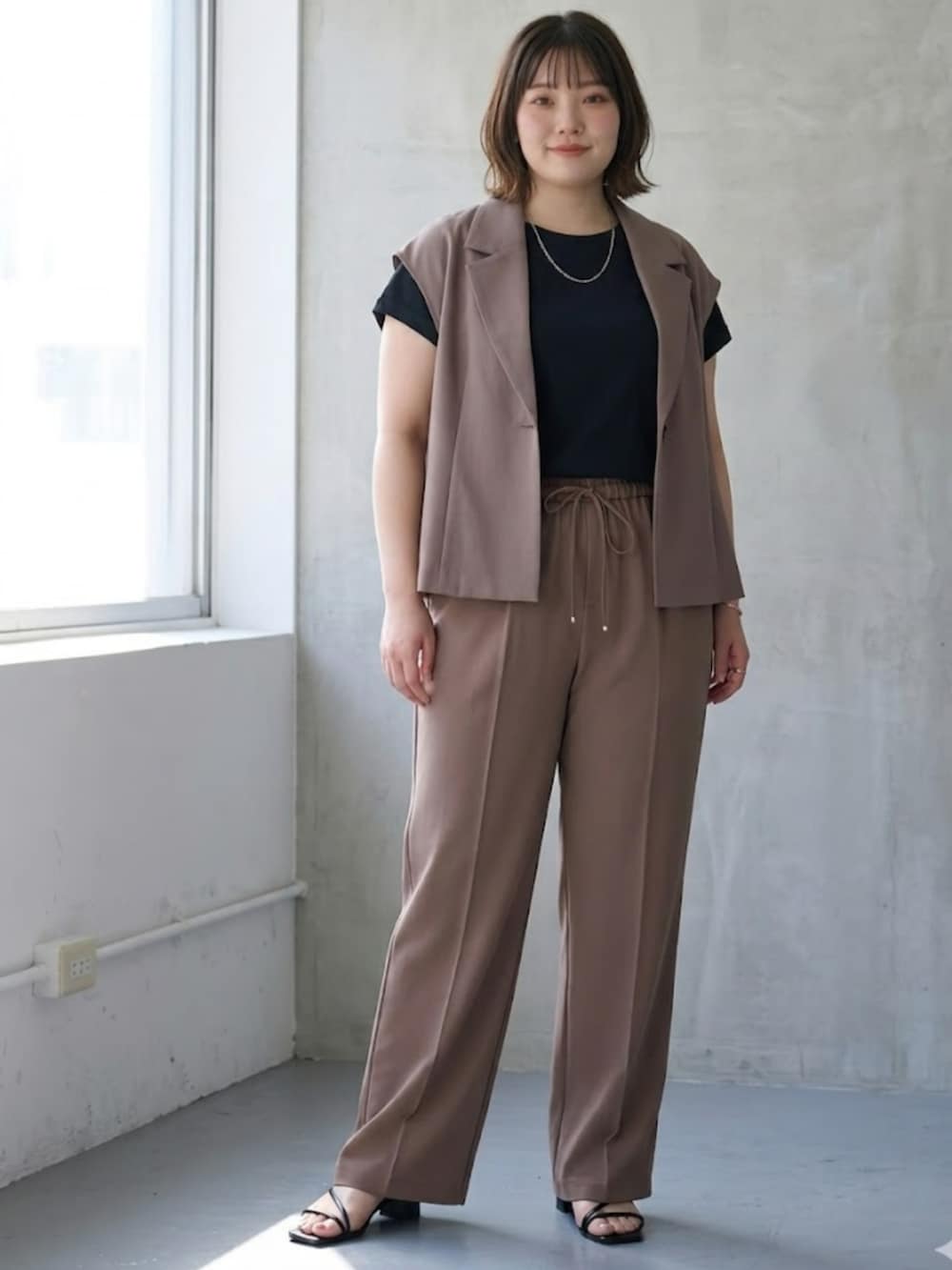 ベージュ系のスーツセット、ブラウン系のパンツ、ブラック系のTシャツ/カットソーを着用したレディースの春コーディネートの2枚目の写真