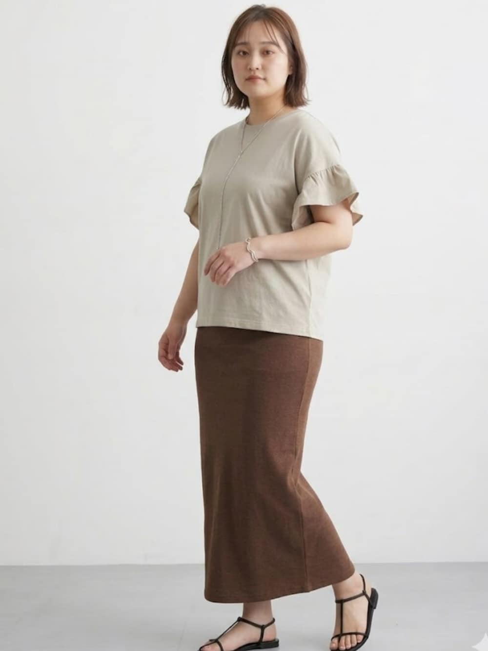 ブラウン系のスカート、ベージュ系のTシャツ/カットソーを着用したレディースの春コーディネートの2枚目の写真