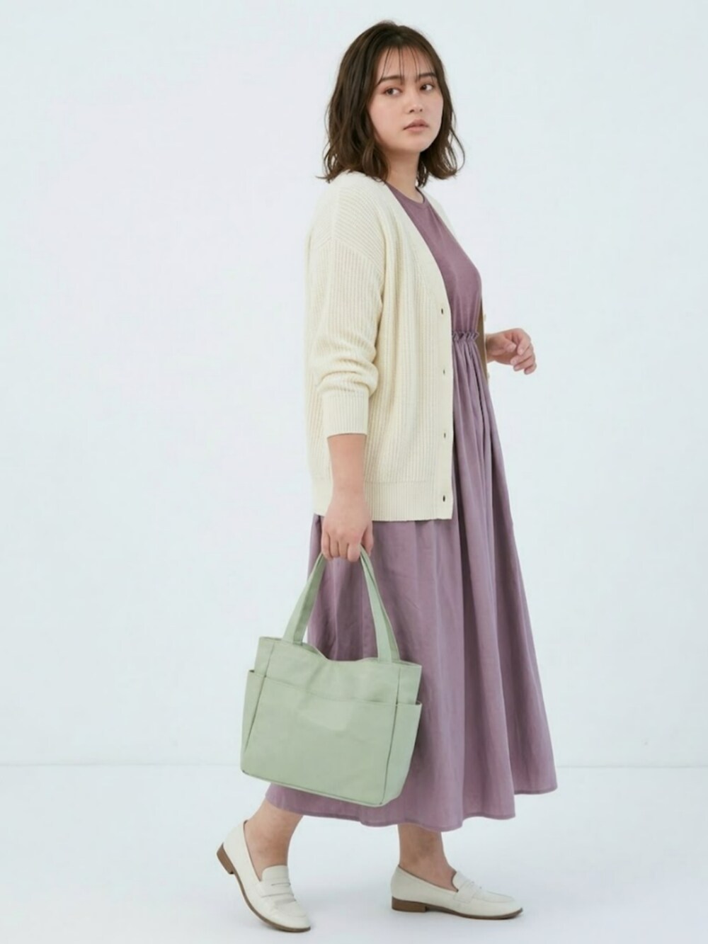 ピンク系のワンピース、ホワイト系のカーディガン/ボレロ、グリーン系のトートバッグを着用したレディースの春コーディネートの3枚目の写真