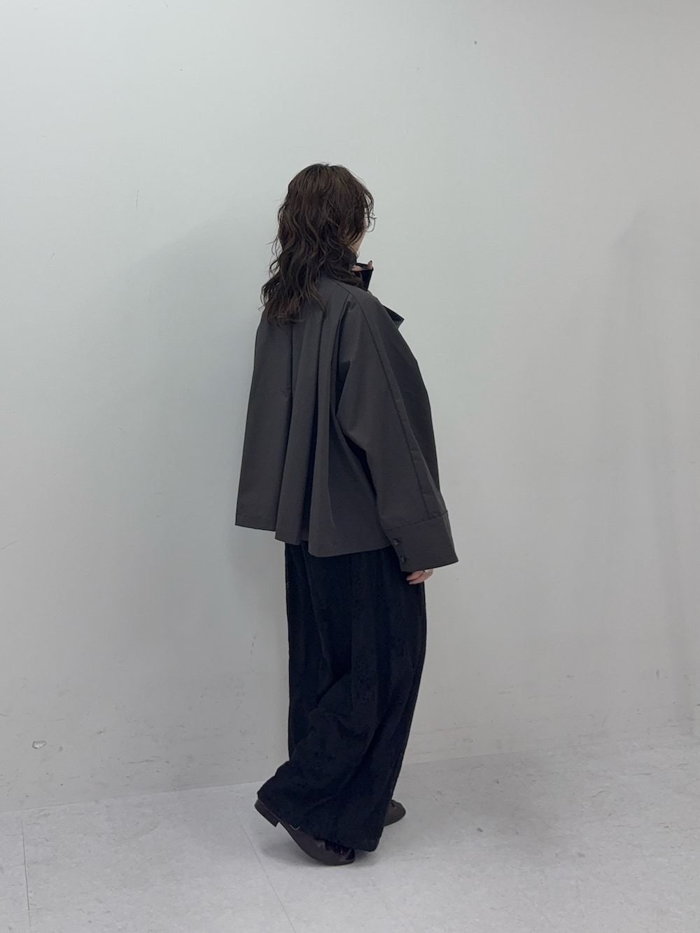 グレー系のステンカラーコート、ブラック系のその他パンツ、ブラック系のその他シューズを着用したレディースの冬コーディネートの2枚目の写真