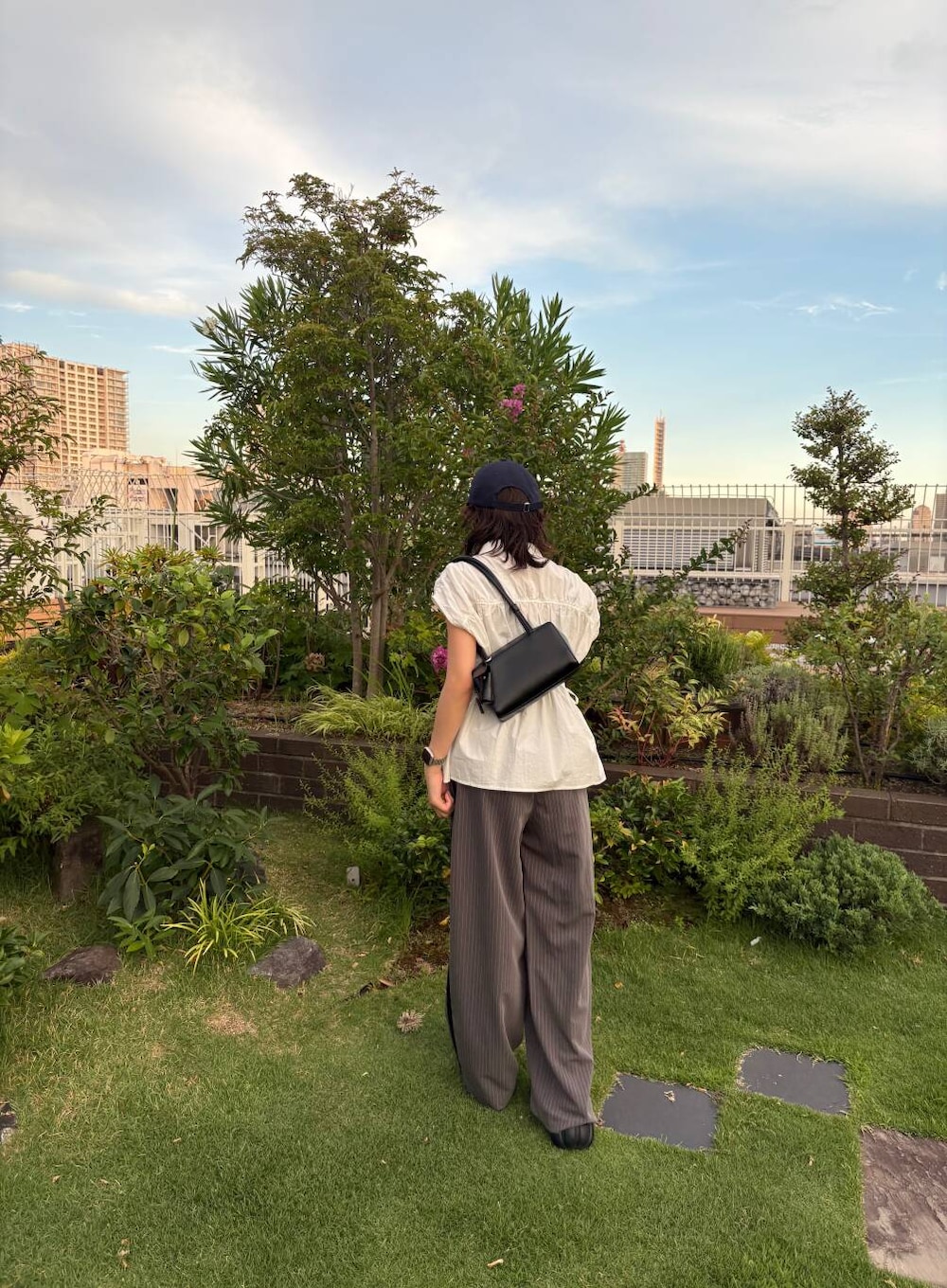 ブラック系のショルダーバッグ、グレー系のその他パンツ、ホワイト系のシャツ/ブラウスを着用したレディースの夏コーディネートの4枚目の写真