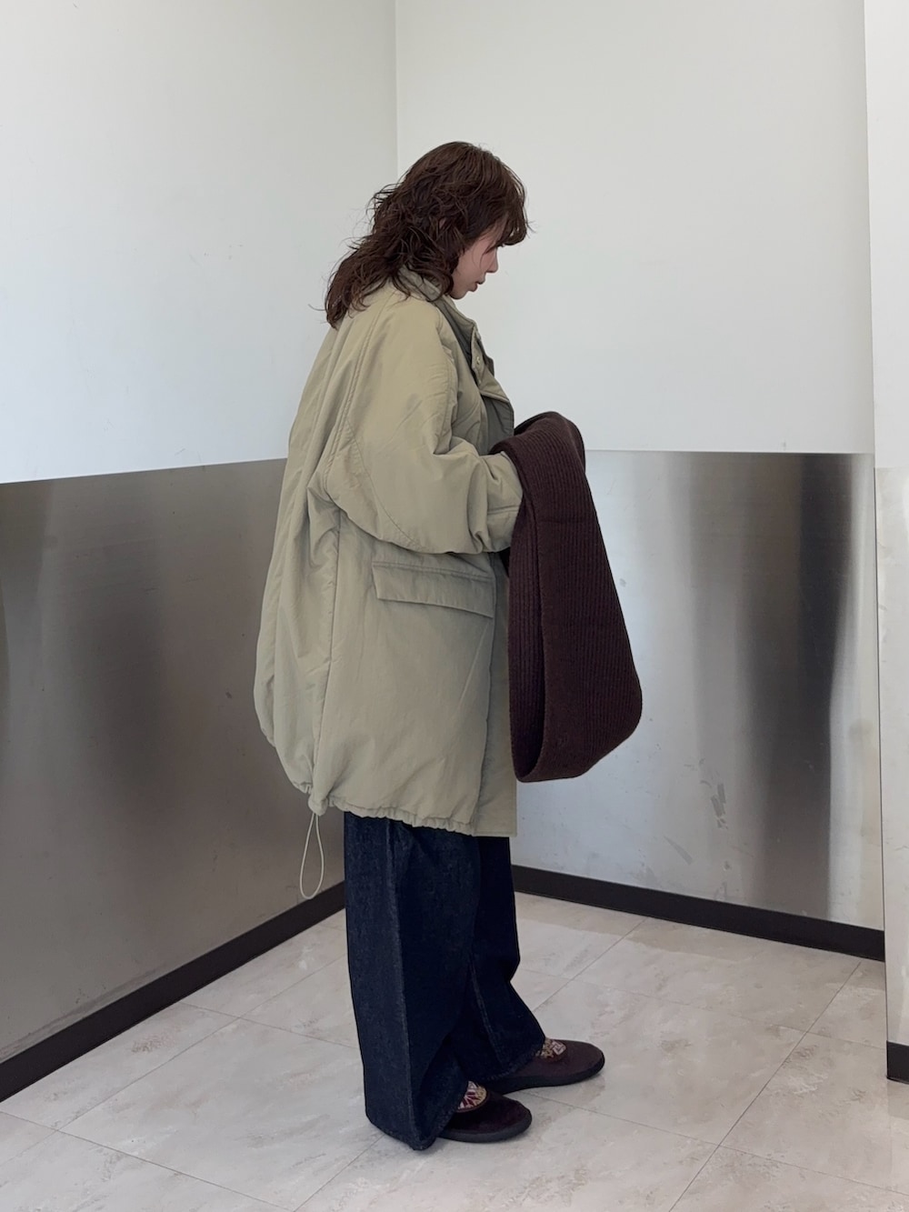 ブラウン系のTシャツ/カットソー、ブルー系のダウンジャケット/コート、ブルー系のデニムパンツを着用したレディースの冬コーディネートの2枚目の写真