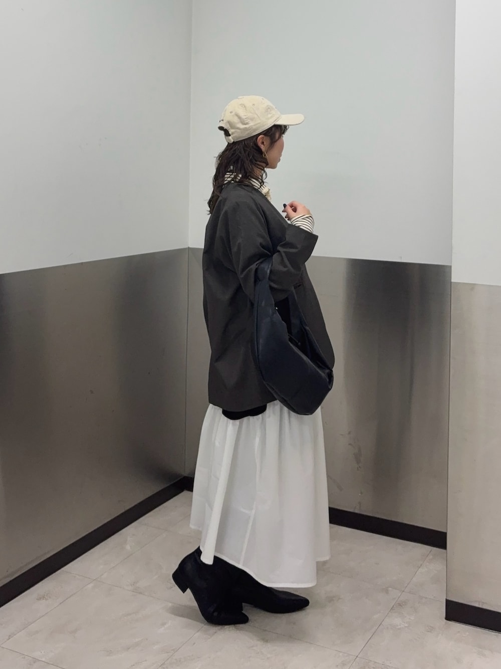 ブラウン系のノーカラージャケット、ホワイト系のスカート、ブラック系のブーツを着用したレディースの冬コーディネートの2枚目の写真