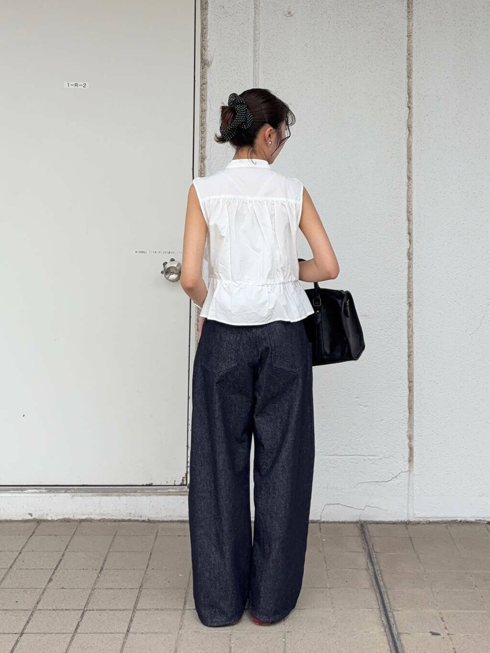 ブラック系のボストンバッグ、ブルー系のデニムパンツ、ホワイト系のシャツ/ブラウスを着用したレディースの春コーディネートの2枚目の写真