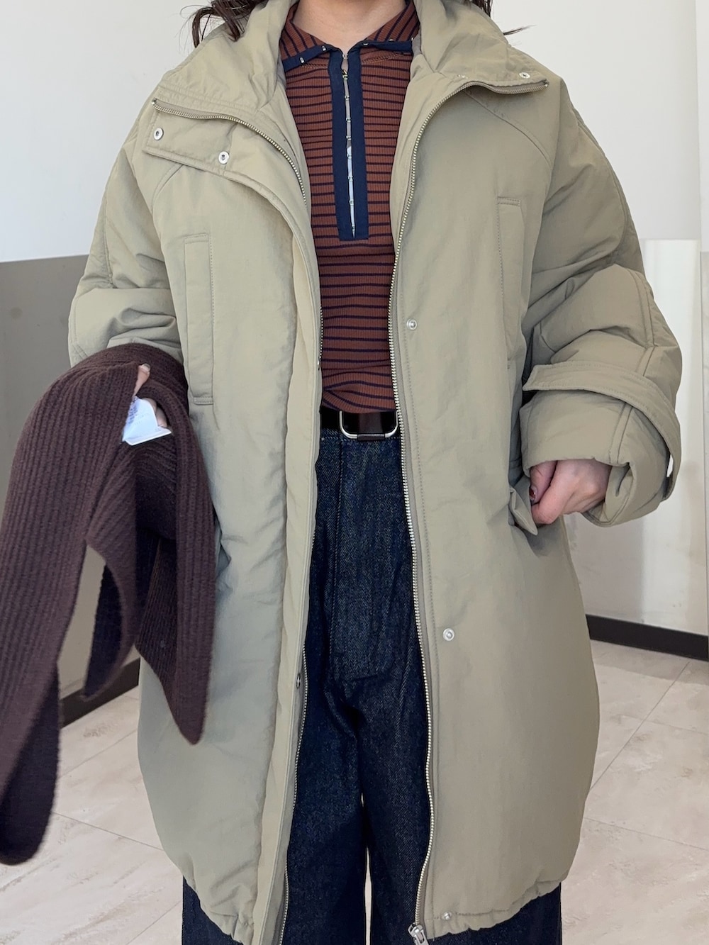 ブラウン系のTシャツ/カットソー、ブルー系のダウンジャケット/コート、ブルー系のデニムパンツを着用したレディースの冬コーディネートの4枚目の写真