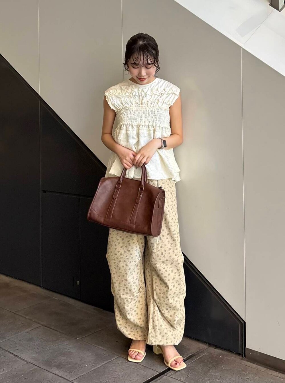 ブラウン系のボストンバッグ、ベージュ系のその他パンツ、イエロー系のサンダルを着用したレディースの夏コーディネートの2枚目の写真