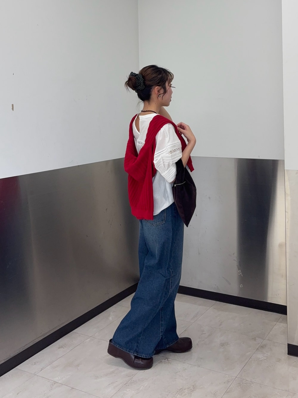 レッド系のニット/セーター、ブルー系のデニムパンツ、ブラウン系のその他シューズを着用したレディースの春コーディネートの2枚目の写真