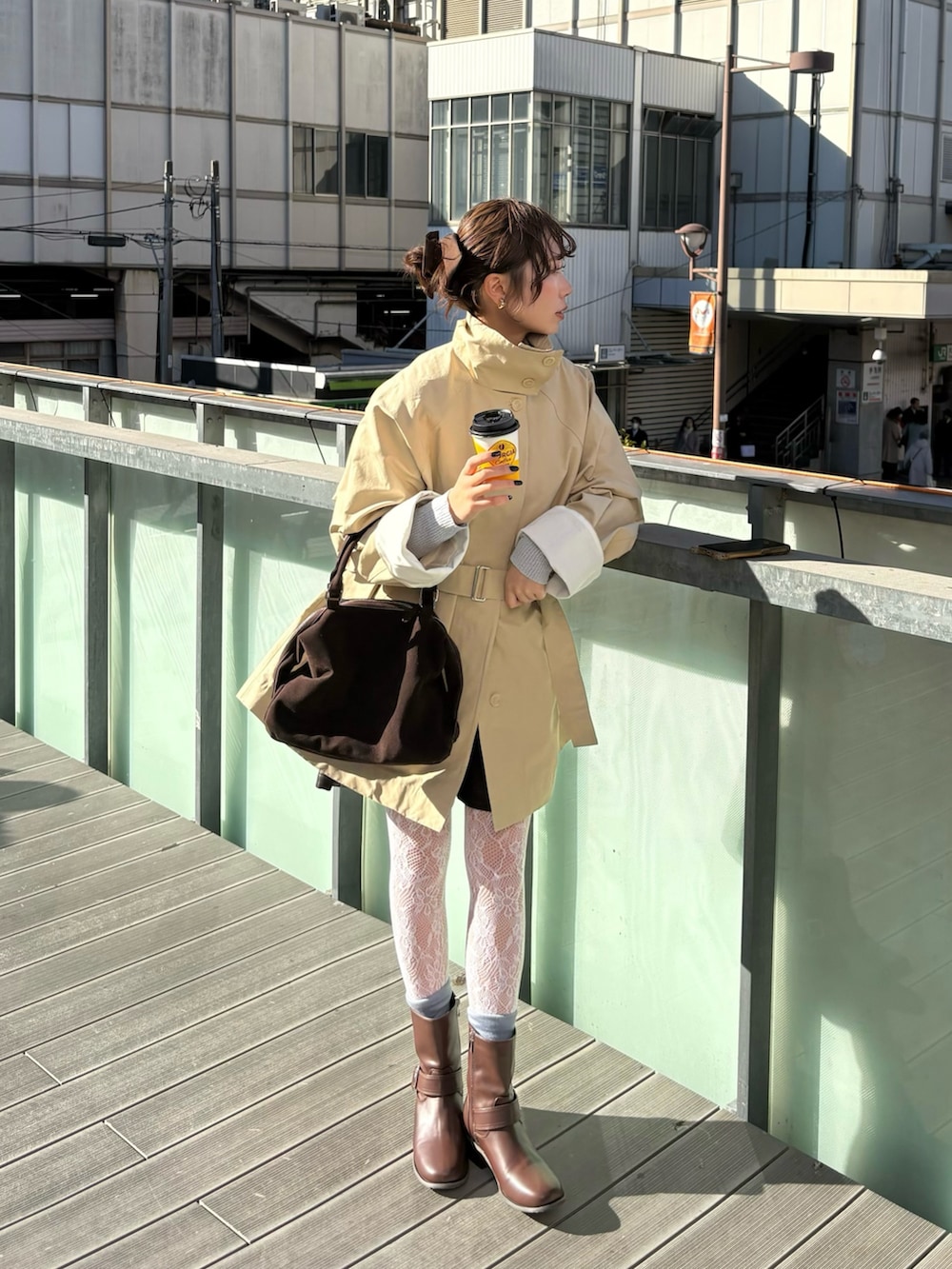 ベージュ系のその他アウター、ブラウン系のブーツ、ブラウン系のボストンバッグを着用したレディースの冬コーディネートの2枚目の写真