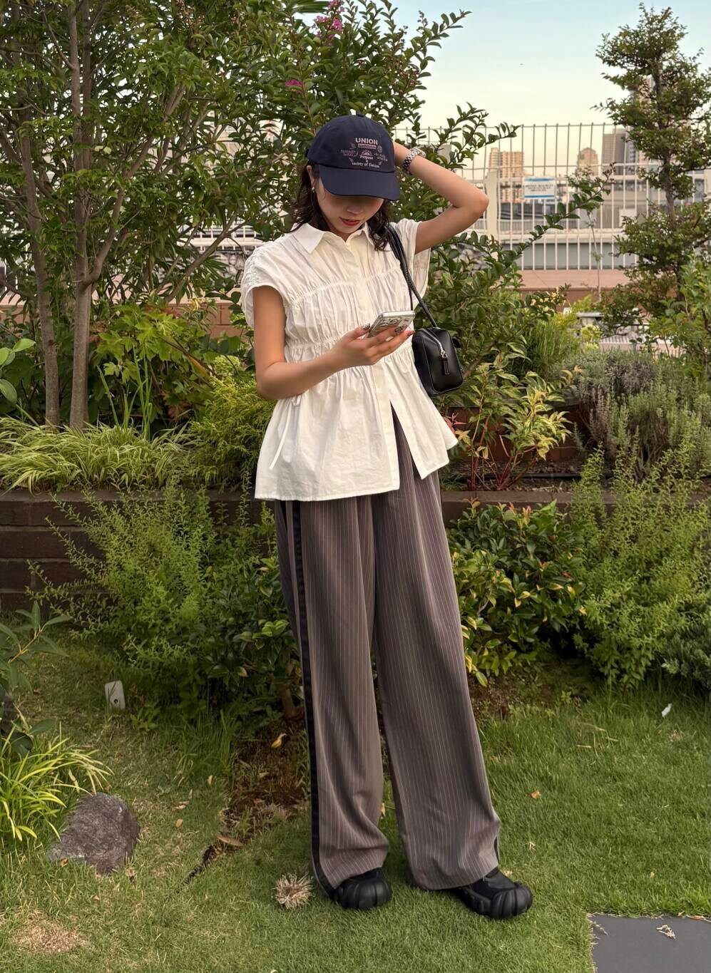 ブラック系のショルダーバッグ、グレー系のその他パンツ、ホワイト系のシャツ/ブラウスを着用したレディースの夏コーディネートの2枚目の写真