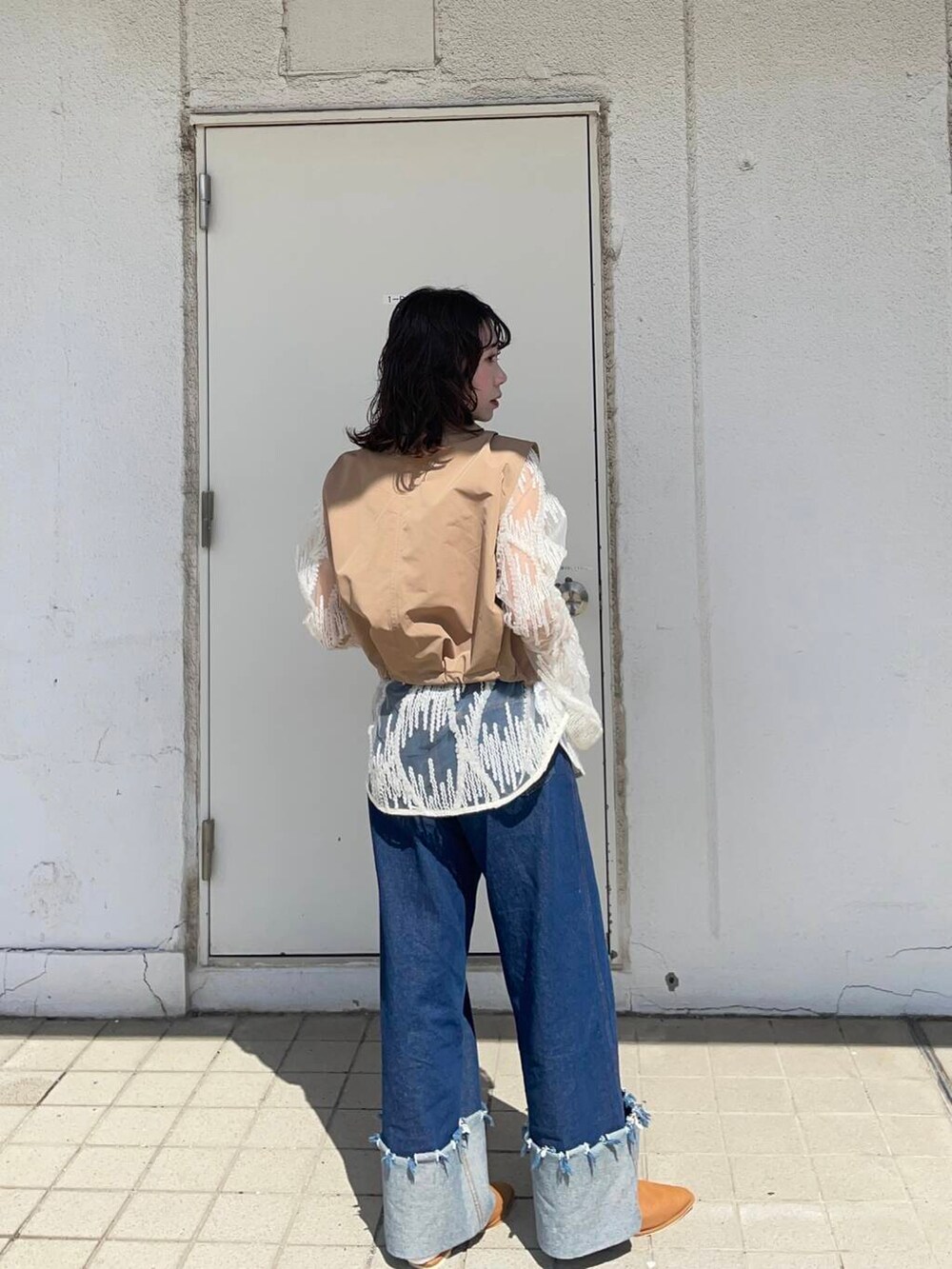 イエロー系のベスト、ブルー系のデニムパンツ、ホワイト系のシャツ/ブラウスを着用したレディースの春コーディネートの2枚目の写真