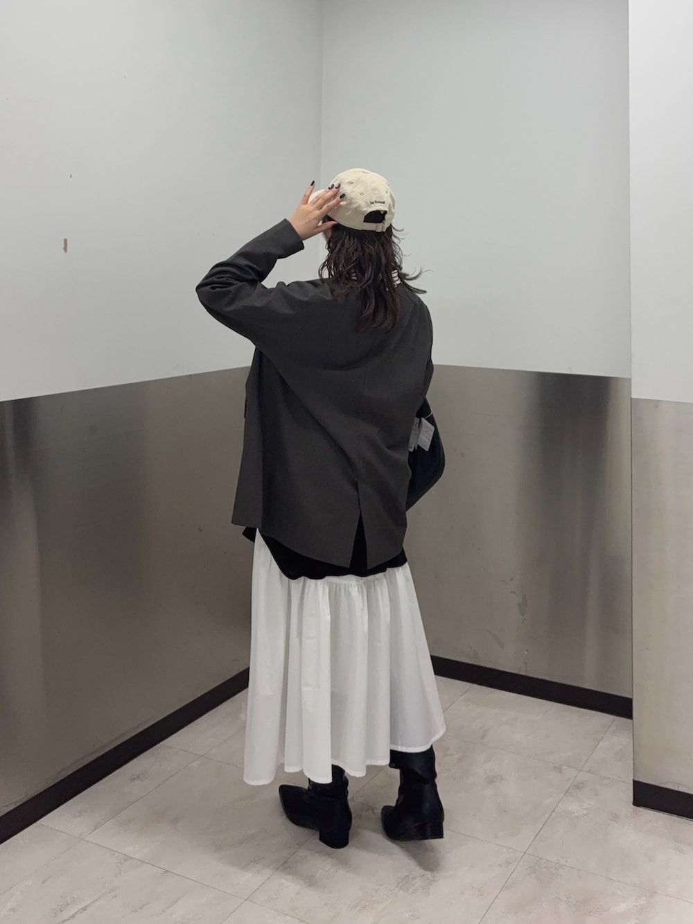 ブラウン系のノーカラージャケット、ホワイト系のスカート、ブラック系のブーツを着用したレディースの冬コーディネートの3枚目の写真