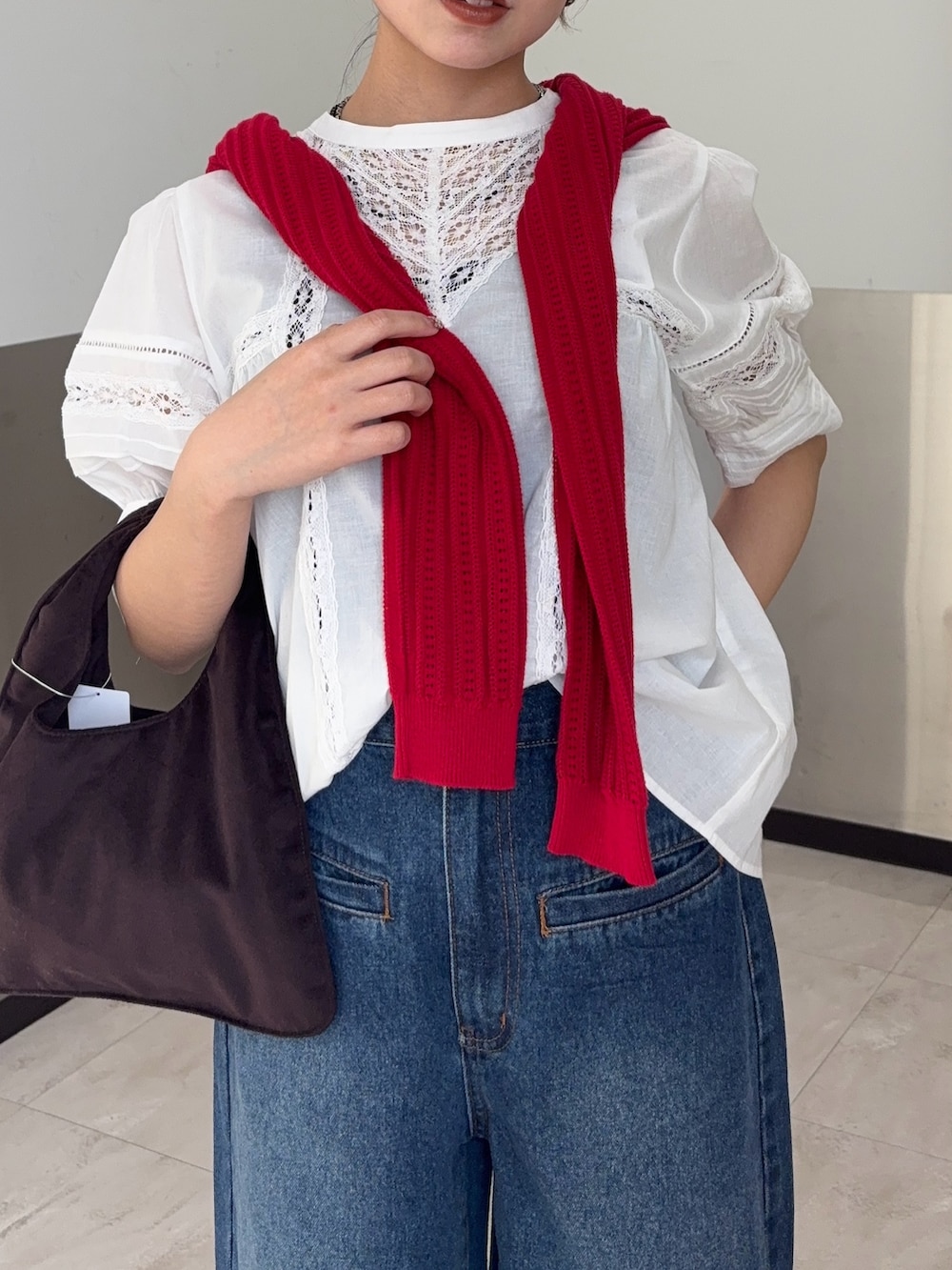 レッド系のニット/セーター、ブルー系のデニムパンツ、ブラウン系のその他シューズを着用したレディースの春コーディネートの4枚目の写真