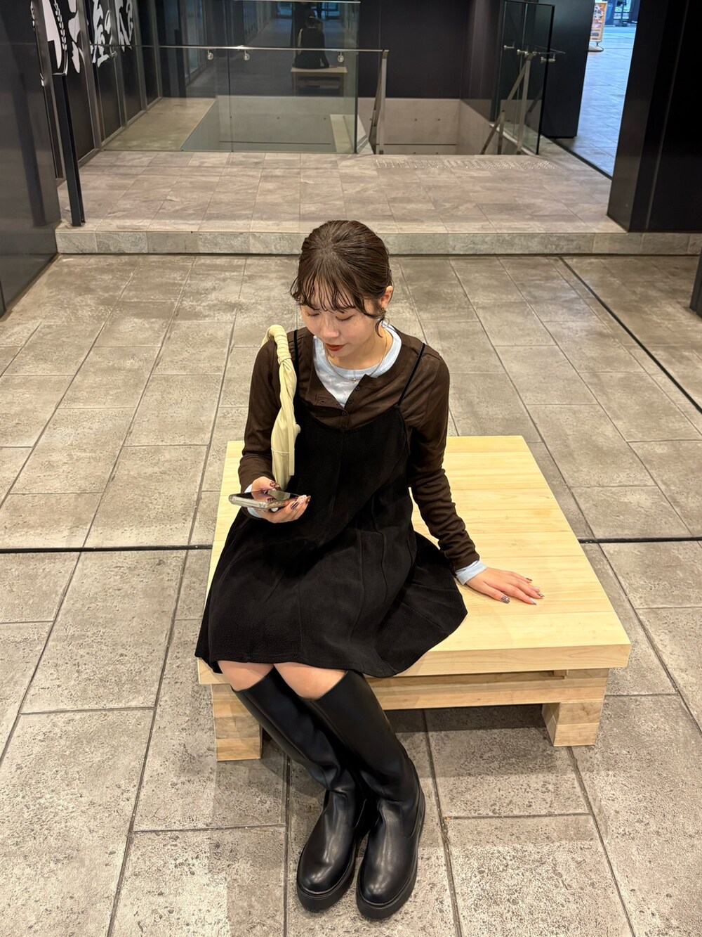 ブラック系のワンピース、ブラウン系のTシャツ/カットソー、ブラック系のブーツを着用したレディースの秋コーディネートの2枚目の写真