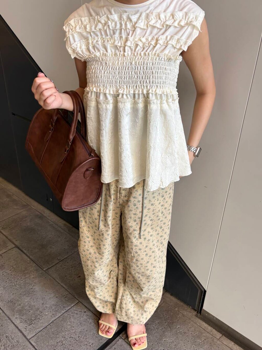 ブラウン系のボストンバッグ、ベージュ系のその他パンツ、イエロー系のサンダルを着用したレディースの夏コーディネートの4枚目の写真