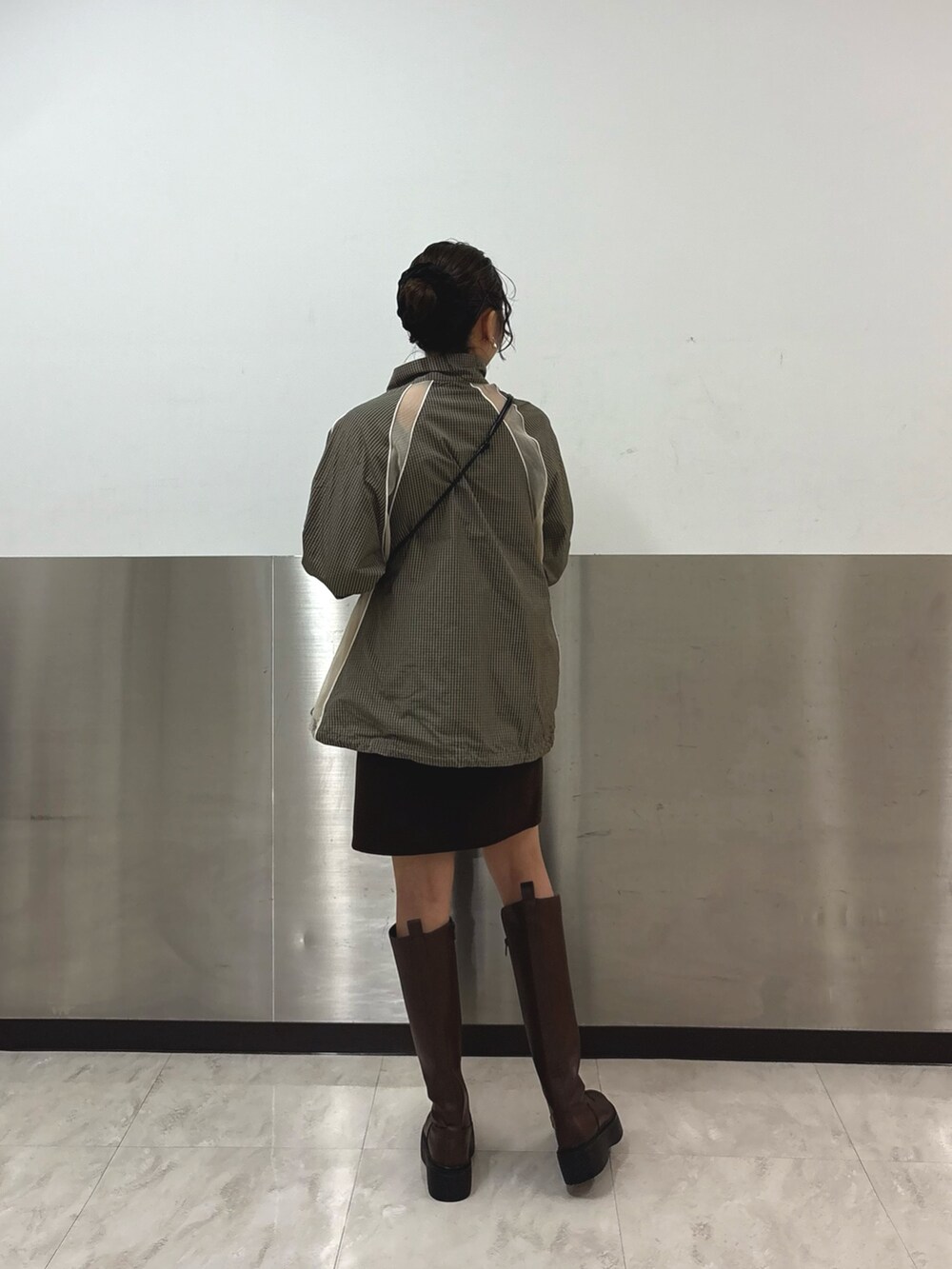 グリーン系のブルゾン、ブラウン系のスカート、ブラウン系のブーツを着用したレディースの秋コーディネートの2枚目の写真