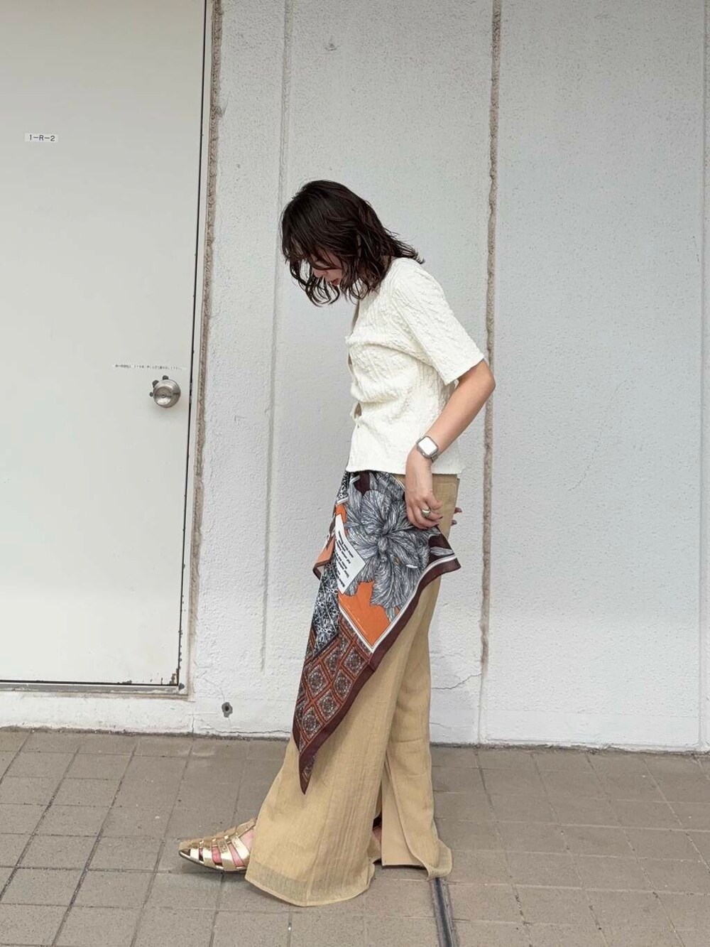 ベージュ系のキャミソール、ゴールド系のサンダル、ホワイト系のTシャツ/カットソーを着用したレディースの春コーディネートの2枚目の写真