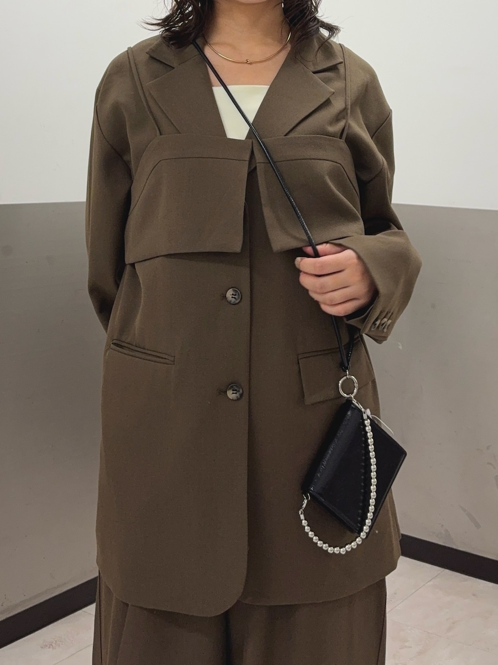 ブラウン系のその他アウター、ブラウン系のその他パンツ、ホワイト系のタンクトップを着用したレディースの秋コーディネートの5枚目の写真