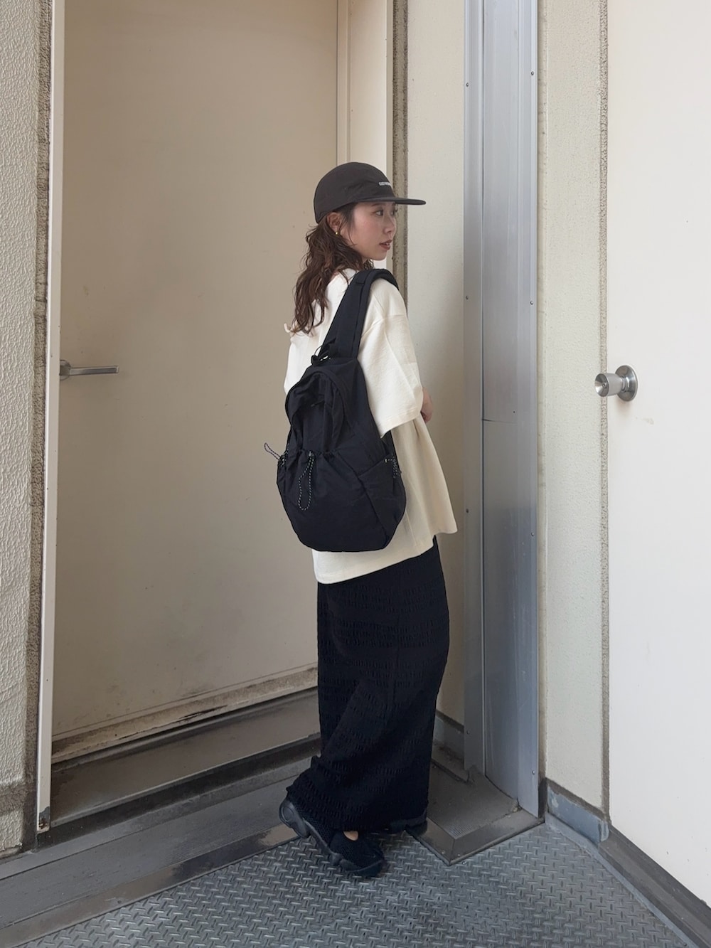 ホワイト系のTシャツ/カットソー、ブラック系のスカート、ブラック系のバックパック/リュックを着用したレディースの夏コーディネートの2枚目の写真