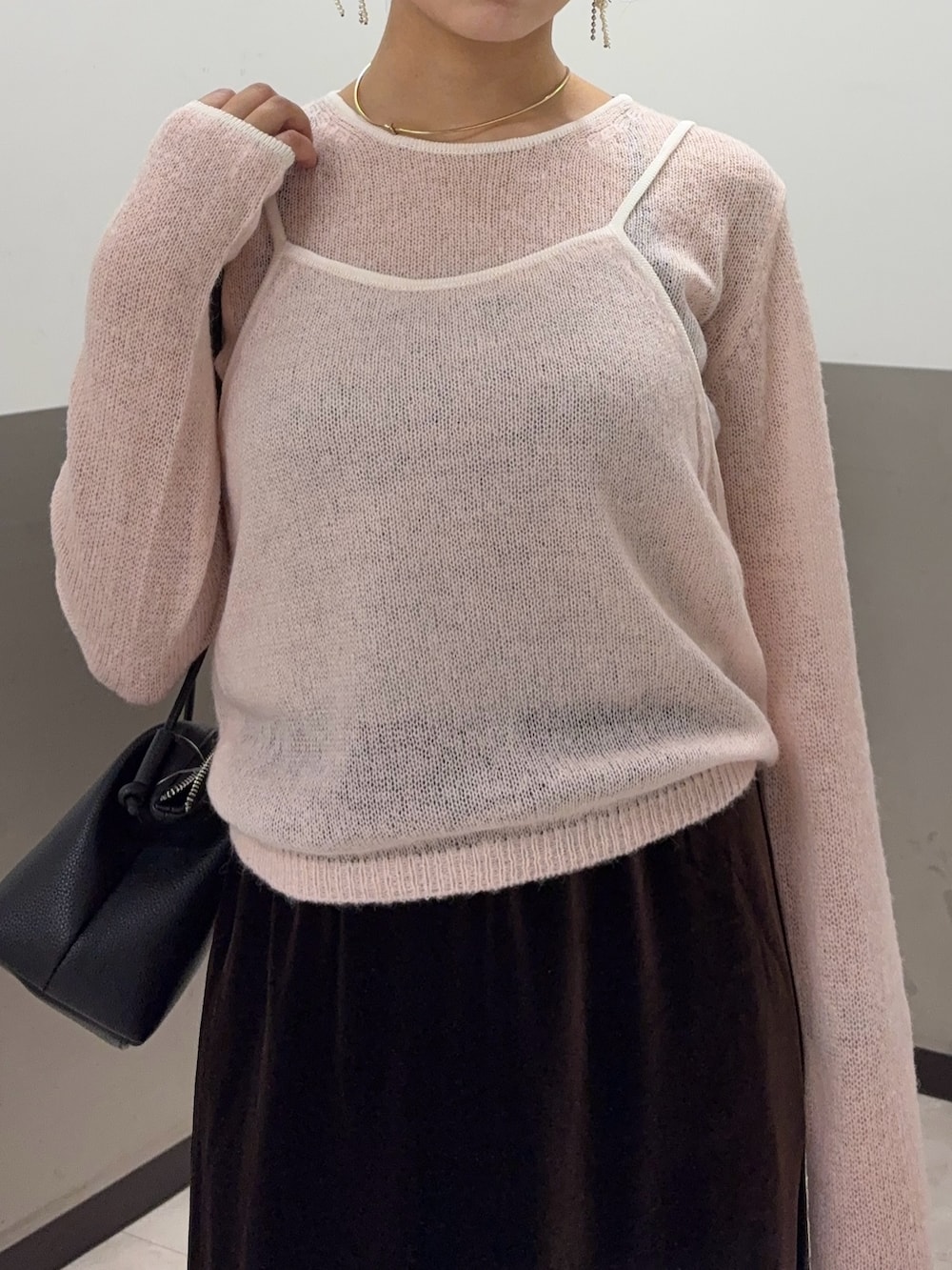 ブラウン系のスカート、ピンク系のニット/セーター、ブラック系のショルダーバッグを着用したレディースの秋コーディネートの4枚目の写真