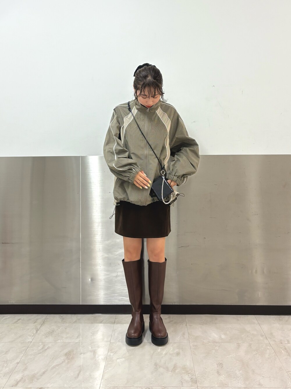 グリーン系のブルゾン、ブラウン系のスカート、ブラウン系のブーツを着用したレディースの秋コーディネートの5枚目の写真