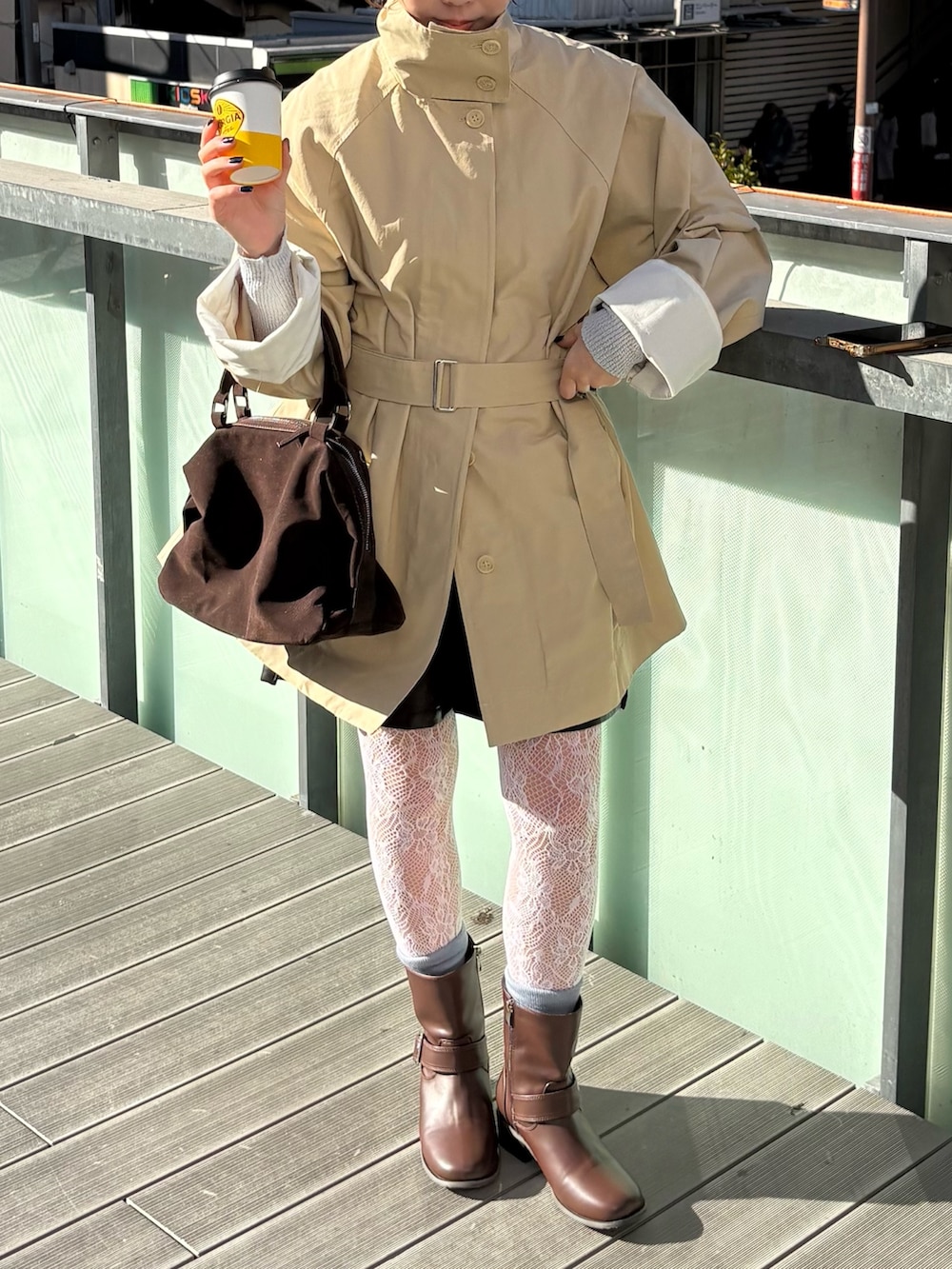 ベージュ系のその他アウター、ブラウン系のブーツ、ブラウン系のボストンバッグを着用したレディースの冬コーディネートの4枚目の写真