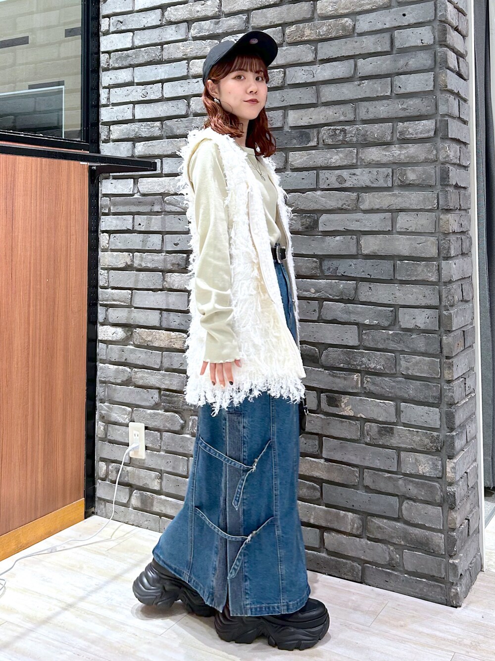 イエロー系のTシャツ/カットソー、ブラック系のショルダーバッグ、ブルー系のデニムスカートを着用したレディースの秋コーディネートの4枚目の写真