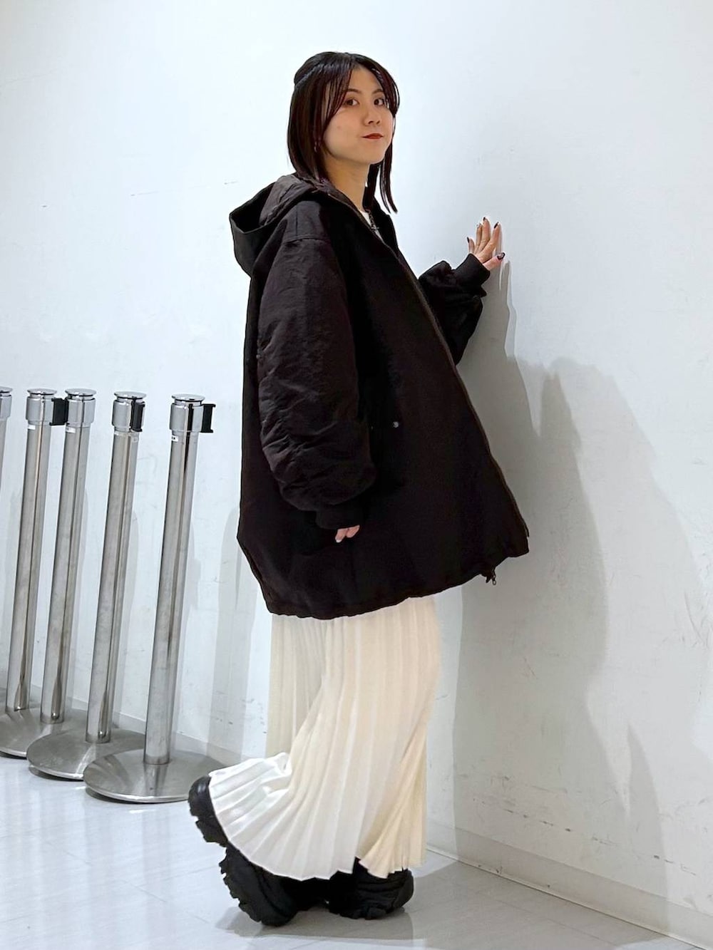 ブラウン系のブルゾン、ホワイト系のニット/セーター、ホワイト系のスカートを着用したレディースの冬コーディネートの4枚目の写真