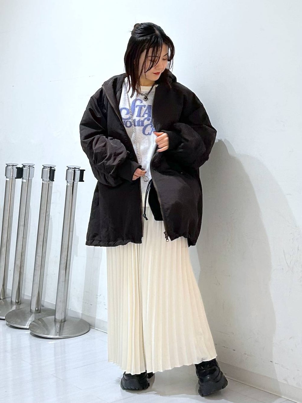 ブラウン系のブルゾン、ホワイト系のニット/セーター、ホワイト系のスカートを着用したレディースの冬コーディネートの2枚目の写真