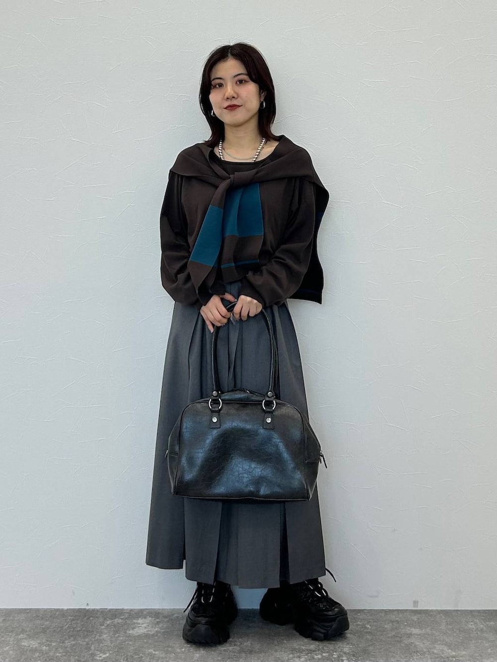 ブラック系のスニーカー、グレー系のボストンバッグ、グレー系のスカートを着用したレディースの秋コーディネートの3枚目の写真