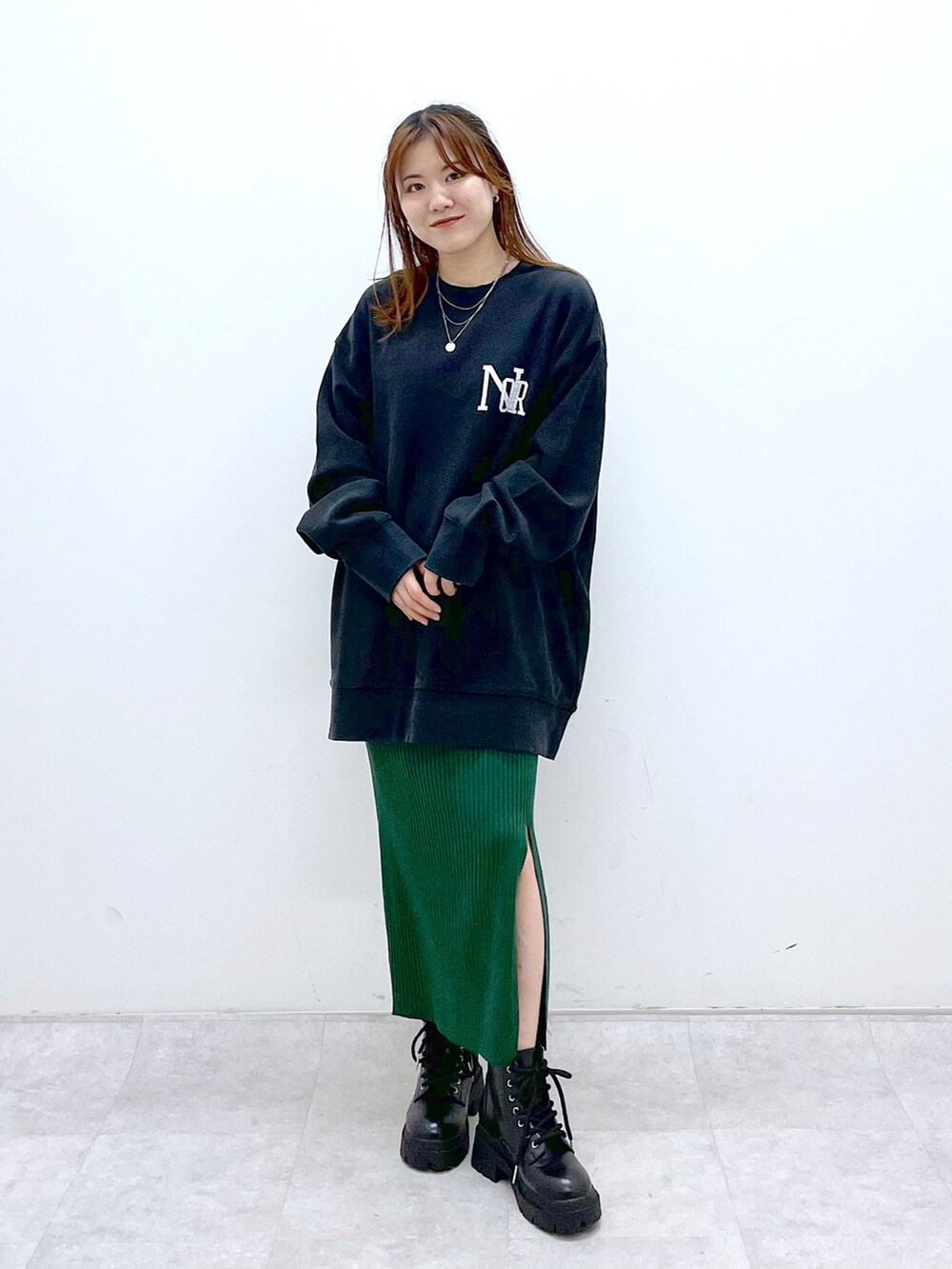 ブラック系のスウェット、グリーン系のワンピース、ブラック系のブーツを着用したレディースの冬コーディネートの2枚目の写真