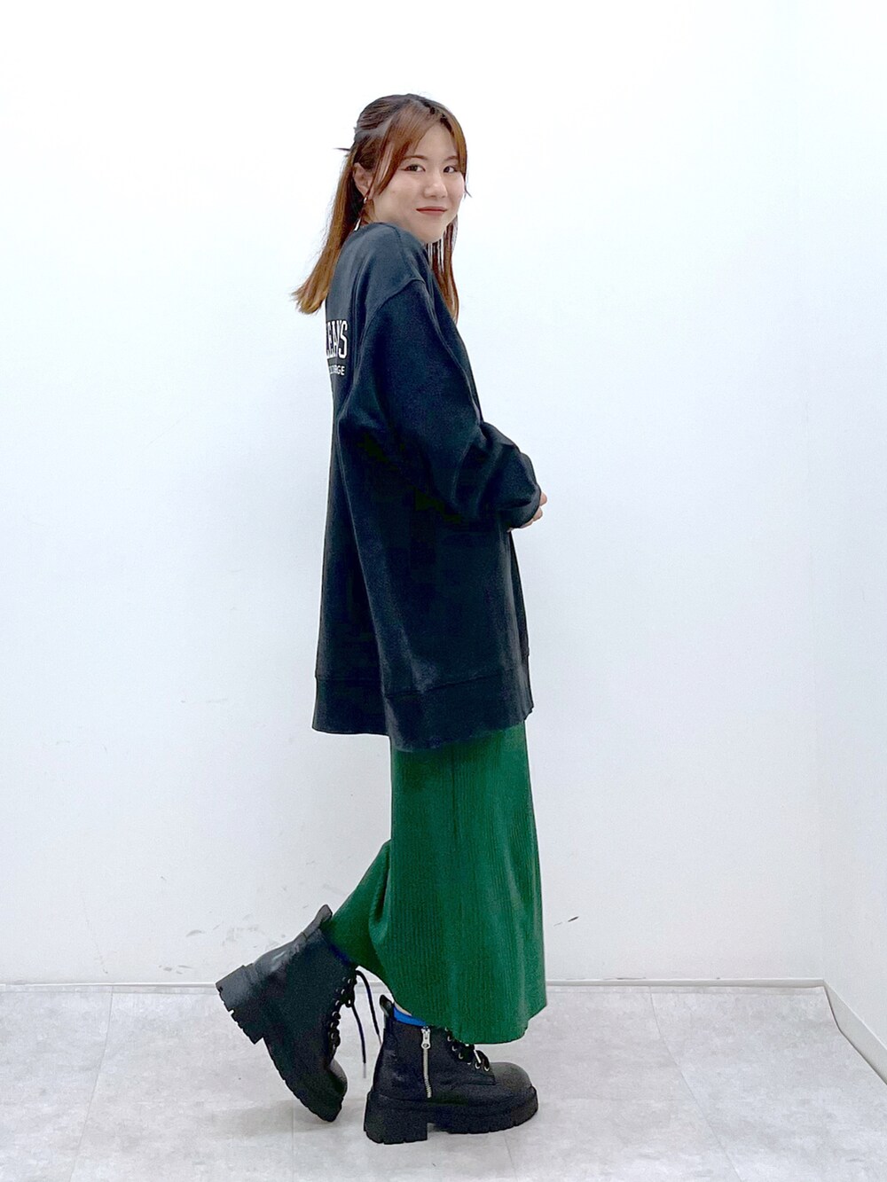 ブラック系のスウェット、グリーン系のワンピース、ブラック系のブーツを着用したレディースの冬コーディネートの3枚目の写真