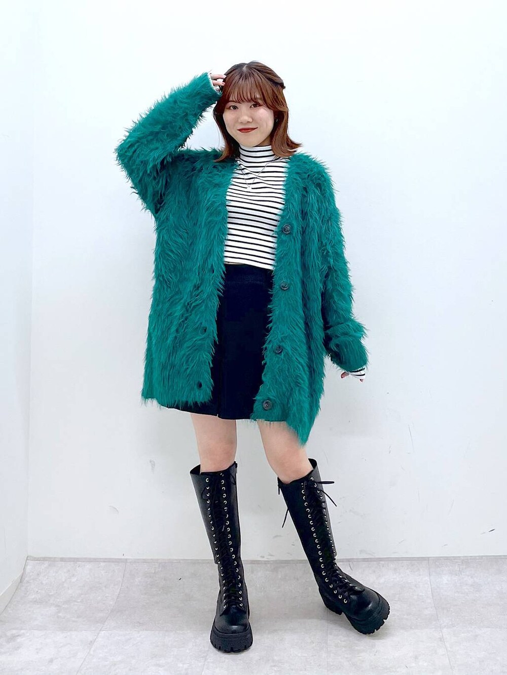 グリーン系のカーディガン/ボレロ、ブラック系のブーツ、ブラック系のその他パンツを着用したレディースの秋コーディネートの2枚目の写真