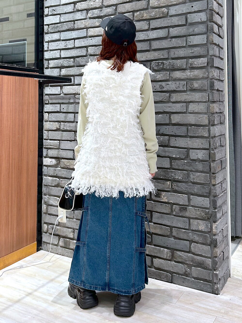 イエロー系のTシャツ/カットソー、ブラック系のショルダーバッグ、ブルー系のデニムスカートを着用したレディースの秋コーディネートの5枚目の写真