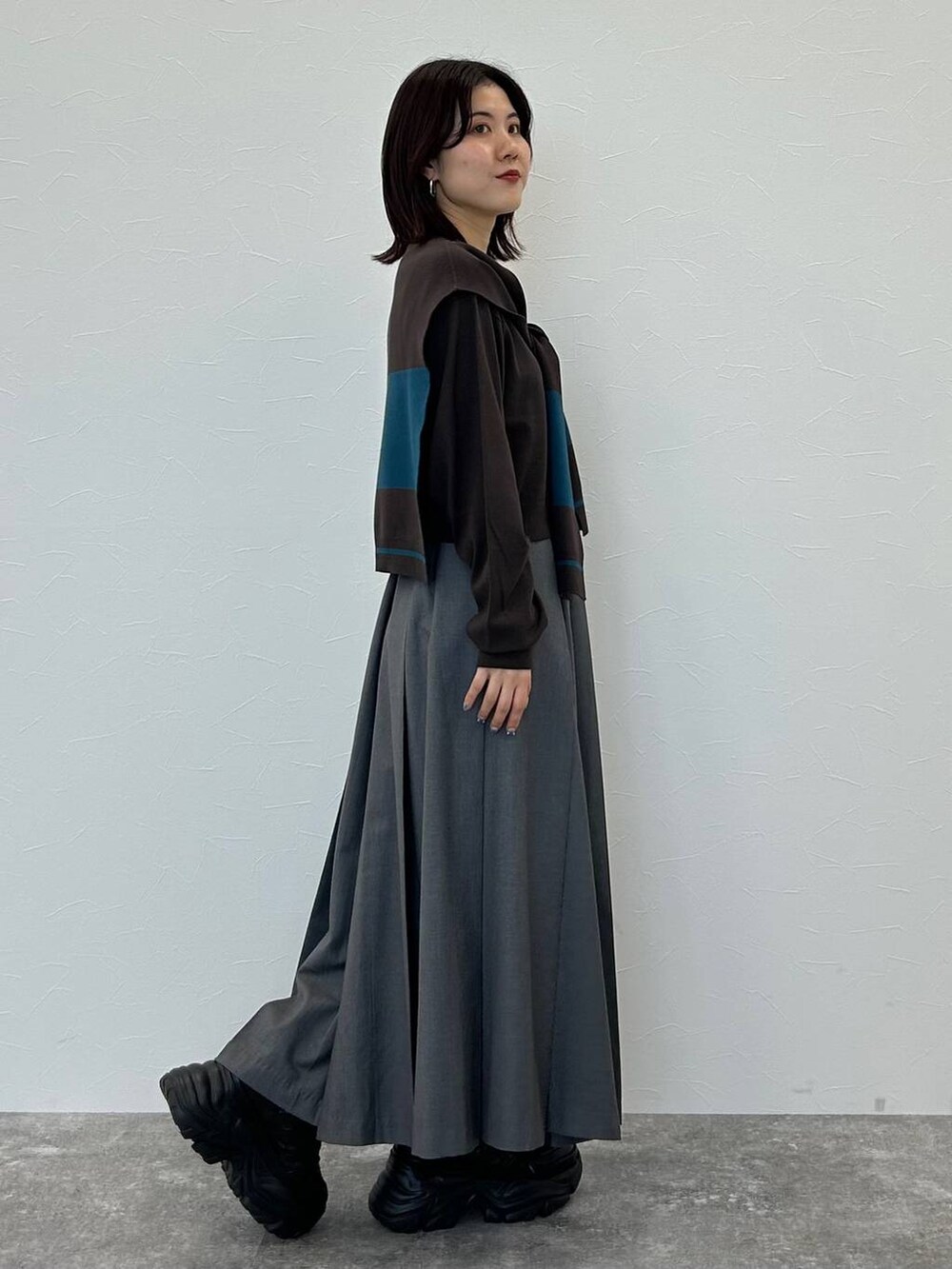 ブラック系のスニーカー、グレー系のボストンバッグ、グレー系のスカートを着用したレディースの秋コーディネートの5枚目の写真