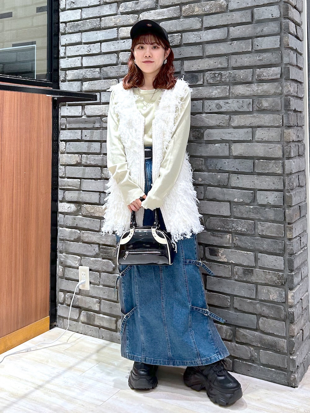 イエロー系のTシャツ/カットソー、ブラック系のショルダーバッグ、ブルー系のデニムスカートを着用したレディースの秋コーディネートの2枚目の写真