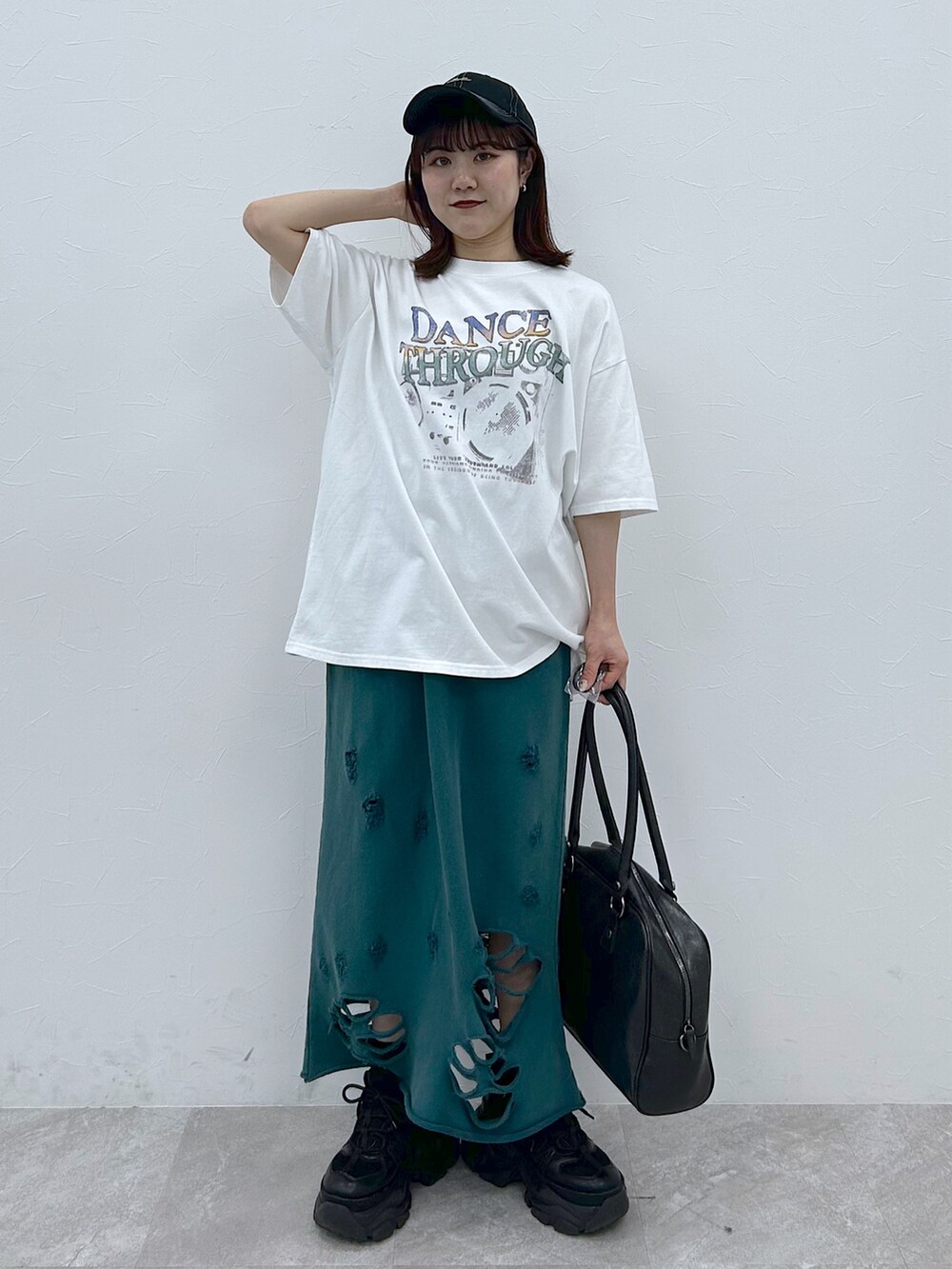 ブラック系のボストンバッグ、ブラック系のスニーカー、ホワイト系のTシャツ/カットソーを着用したレディースの春コーディネートの2枚目の写真