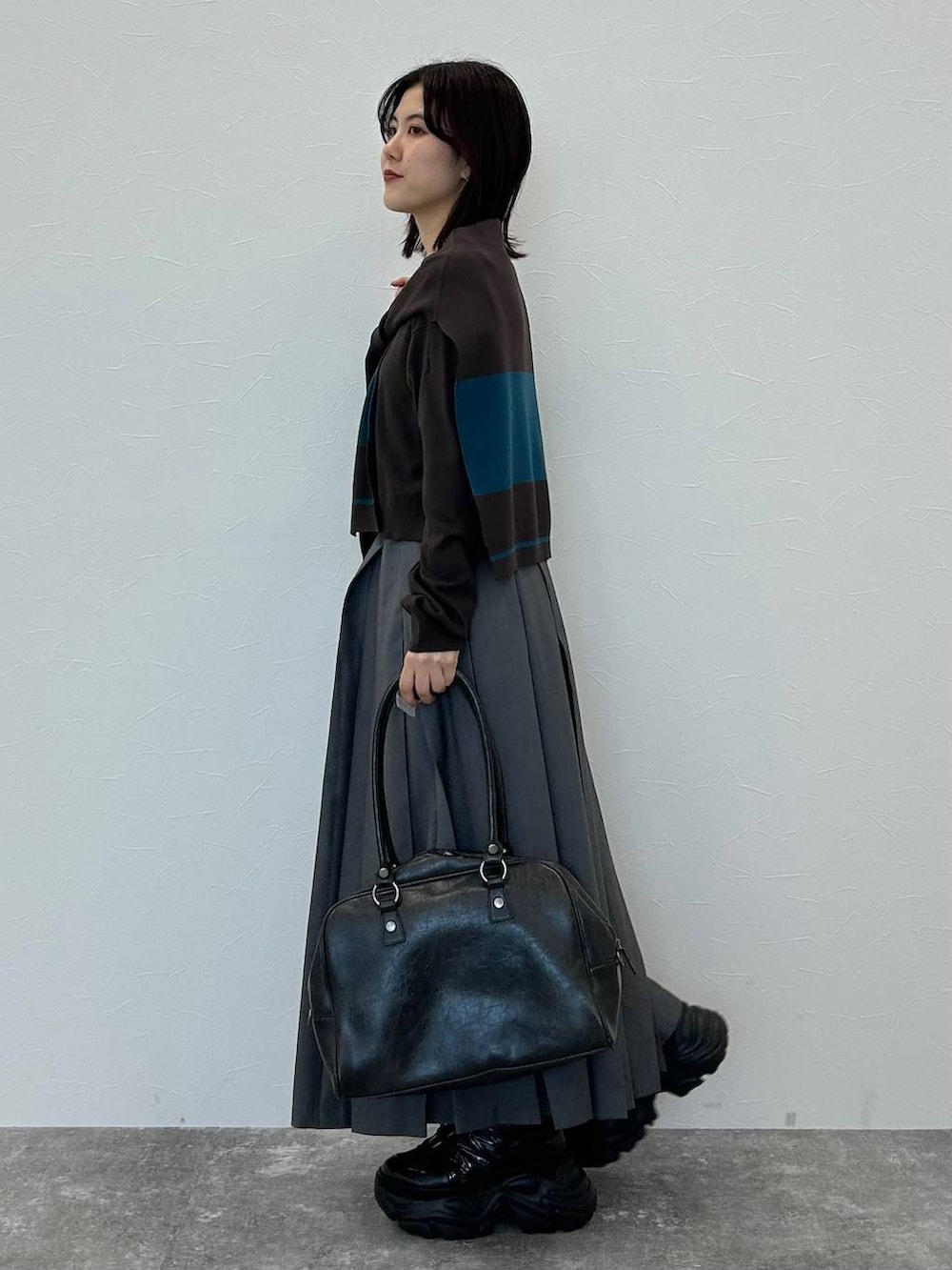 ブラック系のスニーカー、グレー系のボストンバッグ、グレー系のスカートを着用したレディースの秋コーディネートの4枚目の写真