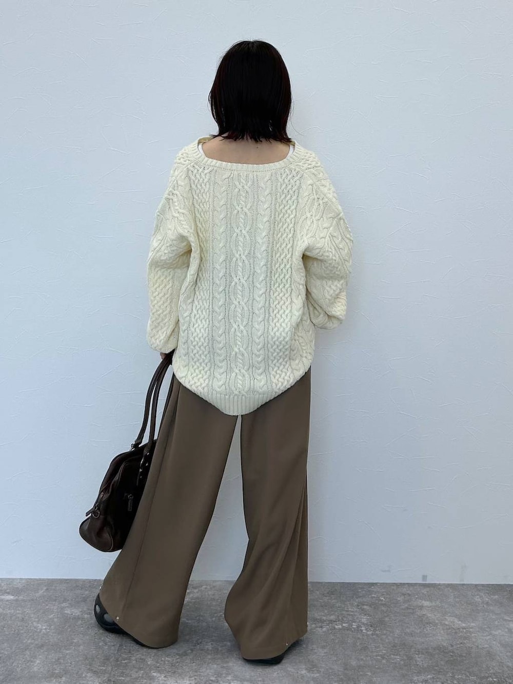 ブラウン系のボストンバッグ、ホワイト系のニット/セーター、ベージュ系のスラックスを着用したレディースの冬コーディネートの6枚目の写真